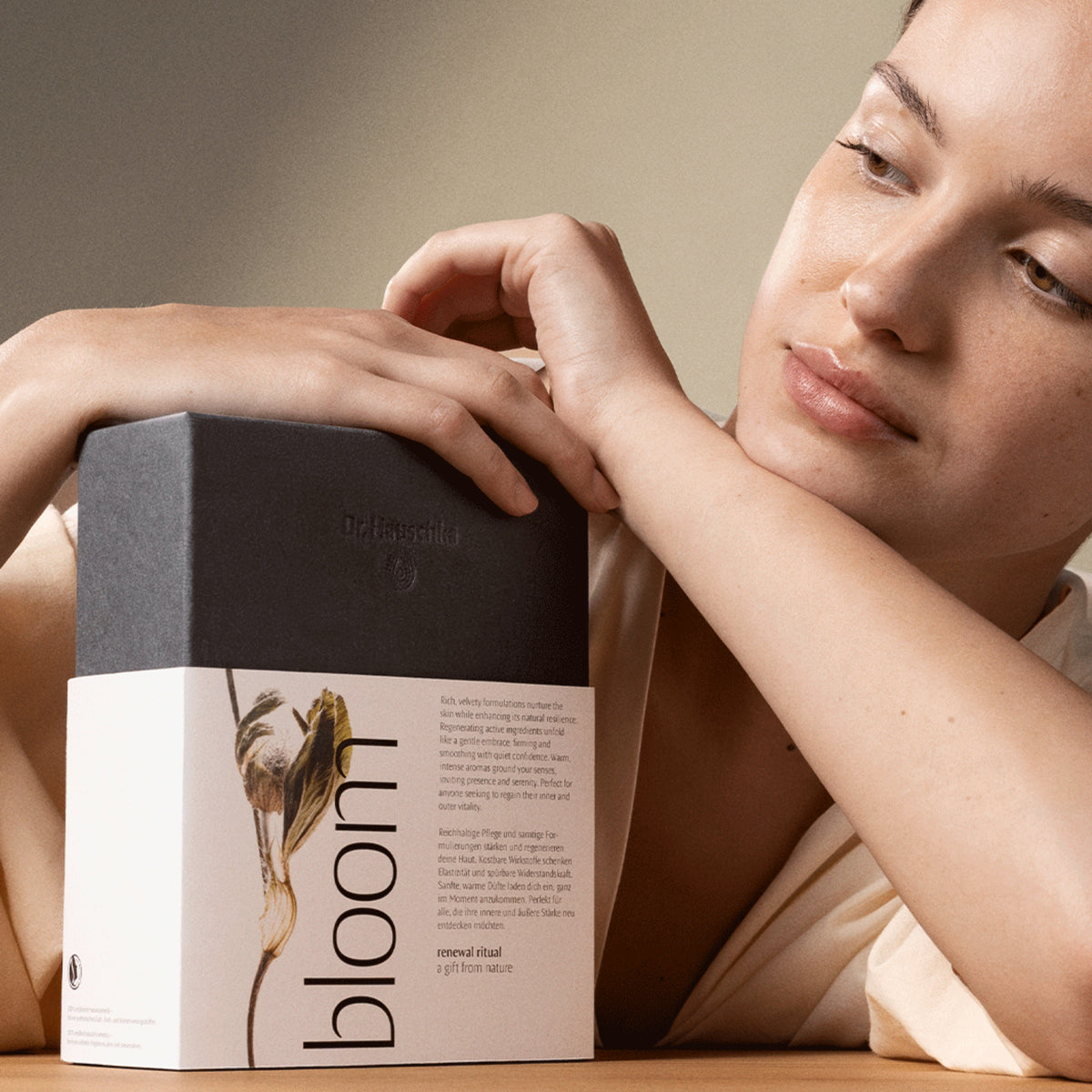 Woman holding Dr. Hauschka Bloom skincare gift set for mature skin